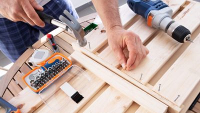 Hands driving nail with hammer into wooden shelf - www.freepik.com